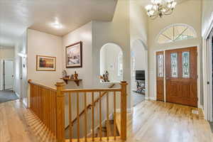 Entryway featuring light wood-type flooring, a chandelier, and arched walkways
