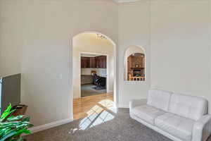 Carpeted living room featuring arched walkways and a towering ceiling