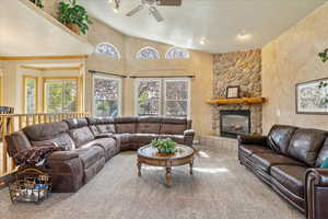 Spacious living room, with tons of natural light, a ceiling fan, high vaulted ceiling, and a cozy fireplace