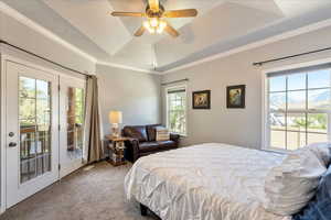 Carpeted bedroom featuring a tray ceiling, access to outside, ornamental molding, and a ceiling fan
