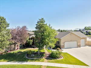 Tree filled front yard, with concrete driveway, an attached 3 car garage, and stucco siding