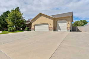 Ranch-style home featuring a garage, driveway, stucco siding, and a gate
