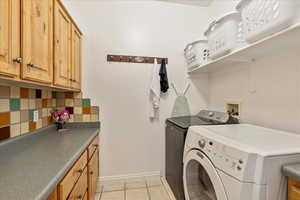 Laundry area with lots of storage cabinets plus laundry sorting baskets above the appliances. light tile patterned floors, and cabinet space