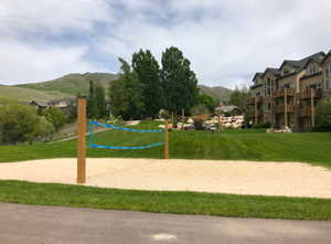Surrounding community featuring volleyball court, a mountain view, and a yard
