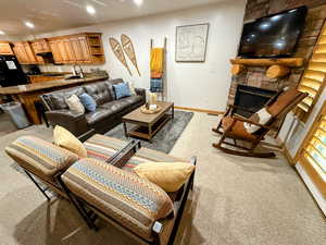 Living area with carpet flooring, a stone fireplace, and recessed lighting