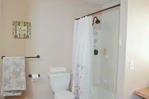 Bathroom with toilet and shower / bathtub combination with curtain