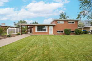 Front of property with driveway, brick siding, and an attached carport