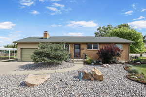 Single story home featuring a garage, driveway, a chimney, brick siding, and roof with shingles