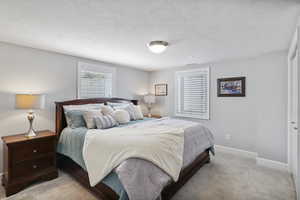 Bedroom with light colored carpet and a textured ceiling
