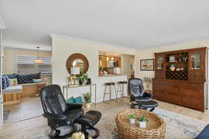 Living area with light wood-type flooring and crown molding
