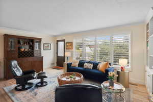 Living area featuring light wood-type flooring, ornamental molding, and a textured ceiling