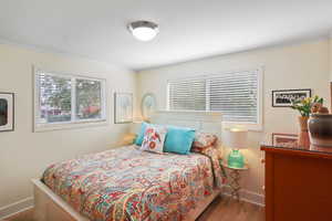 Bedroom featuring multiple windows, wood finished floors, and ornamental molding