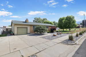 Ranch-style home with a garage, concrete driveway, a chimney, and a mountain view