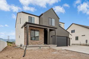 View of front of house with driveway, covered porch, stone siding, and board and batten siding