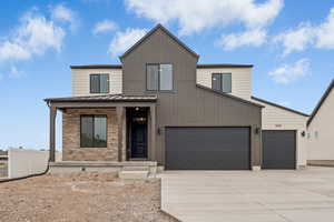 View of front facade featuring concrete driveway, a metal roof, a standing seam roof, brick siding, and a garage