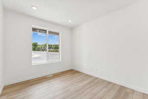 Empty room with light wood-style floors and recessed lighting