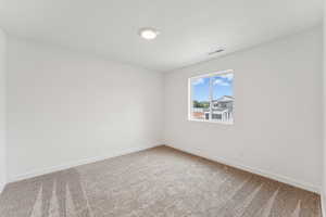 Carpeted spare room featuring baseboards
