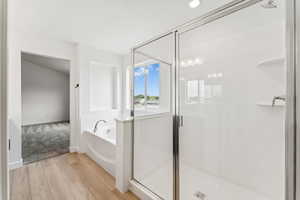 Full bath with a garden tub, a shower stall, and wood finished floors