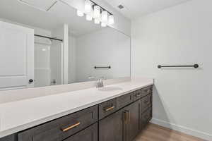 Full bath featuring wood finished floors, a shower, and vanity