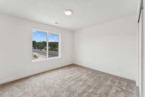 Carpeted spare room featuring baseboards