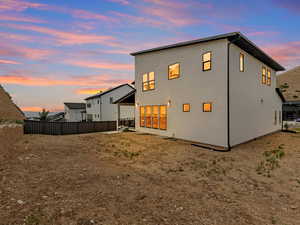 Back of house at dusk with stucco siding and a garage