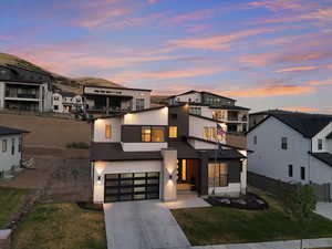 Contemporary house featuring concrete driveway, a garage, stucco siding, and a residential view