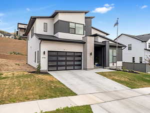 Modern home featuring a garage, driveway, and stucco siding