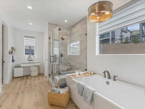 Full bath featuring a freestanding bath, a stall shower, wood finished floors, and recessed lighting