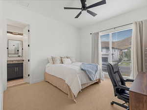 Bedroom featuring light colored carpet, ensuite bathroom, a desk, and ceiling fan