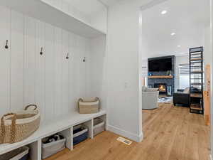 Mudroom featuring light wood-type flooring, a large fireplace, and recessed lighting