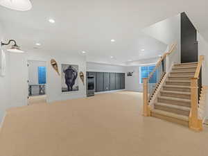 Basement with stairs, carpet flooring, recessed lighting, and wine cooler
