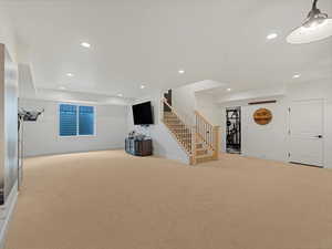 Unfurnished living room with light carpet, stairs, and recessed lighting