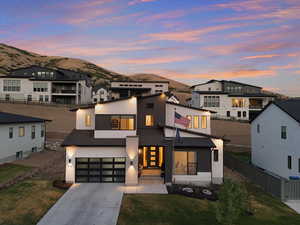 View of front facade featuring driveway, an attached garage, stucco siding, and a shingled roof