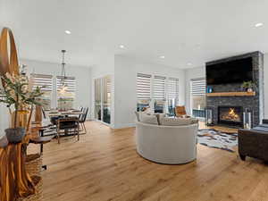 Living room featuring light wood finished floors, a fireplace, recessed lighting, and a chandelier
