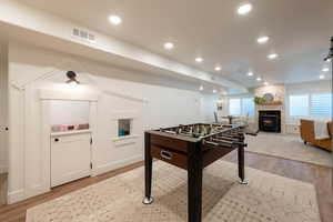 Rec room with light wood-type flooring, recessed lighting, and a fireplace