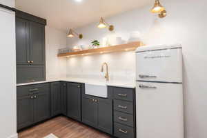 Kitchen featuring freestanding refrigerator, open shelves, light wood-style floors, light countertops, and gray cabinets
