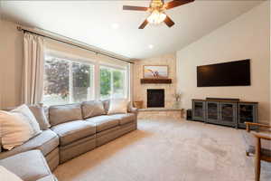 Carpeted living room with vaulted ceiling, a ceiling fan, a fireplace, and recessed lighting