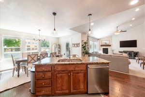 Kitchen with dishwasher, a fireplace, light stone countertops, healthy amount of natural light, and a textured ceiling