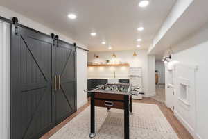 Rec room featuring a barn door, light wood-type flooring, and recessed lighting