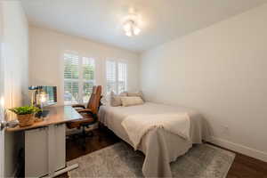 Bedroom featuring dark wood-type flooring and an office area