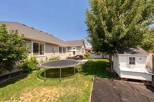 Fenced backyard featuring a trampoline and a shed