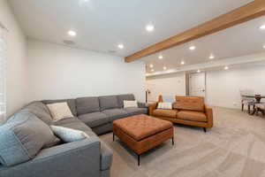 Living area with light carpet, recessed lighting, and beam ceiling