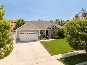 Craftsman house with an attached garage, stone siding, driveway, and a shingled roof