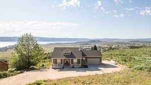 View of front of house with a porch, driveway, a mountain view, a garage, and a shingled roof