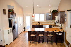 Kitchen with stainless steel appliances, tasteful backsplash, a peninsula, lofted ceiling, and a breakfast bar