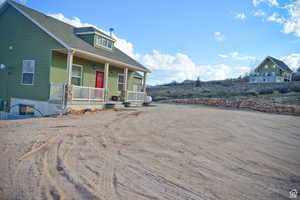 View of side of home featuring a porch and roof with shingles