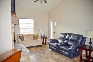 Living room featuring a ceiling fan, wood finished floors, and high vaulted ceiling