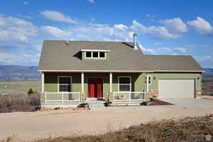 View of front facade with covered porch, a garage, driveway, and roof with shingles
