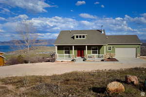 View of front of house with covered porch, roof with shingles, an attached garage, concrete driveway, and stone siding