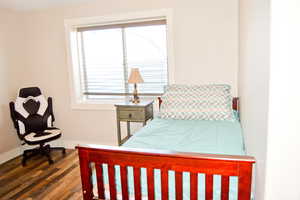 Bedroom with dark wood finished floors and baseboards